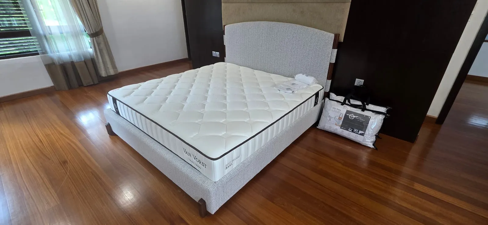 The furnished master bedroom at Villa Mont Kiara — a king bed set against the dark feature wall, garden held behind slatted blinds.